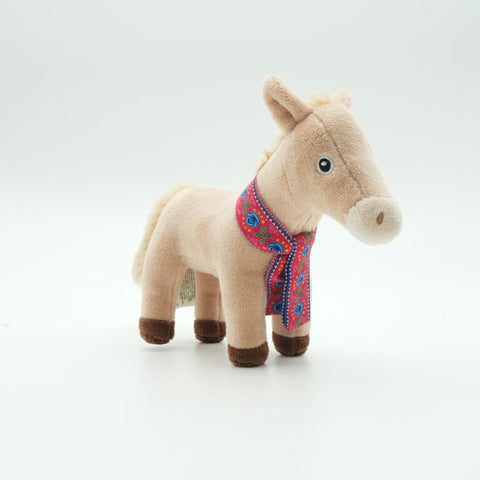 A small plush toy mule standing on a clean white background. The mule is made of soft beige fabric with dark brown hooves and a colourful embroidered scarf in red, blue, and pink.