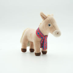 A small plush toy mule standing on a clean white background. The mule is made of soft beige fabric with dark brown hooves and a colourful embroidered scarf in red, blue, and pink.